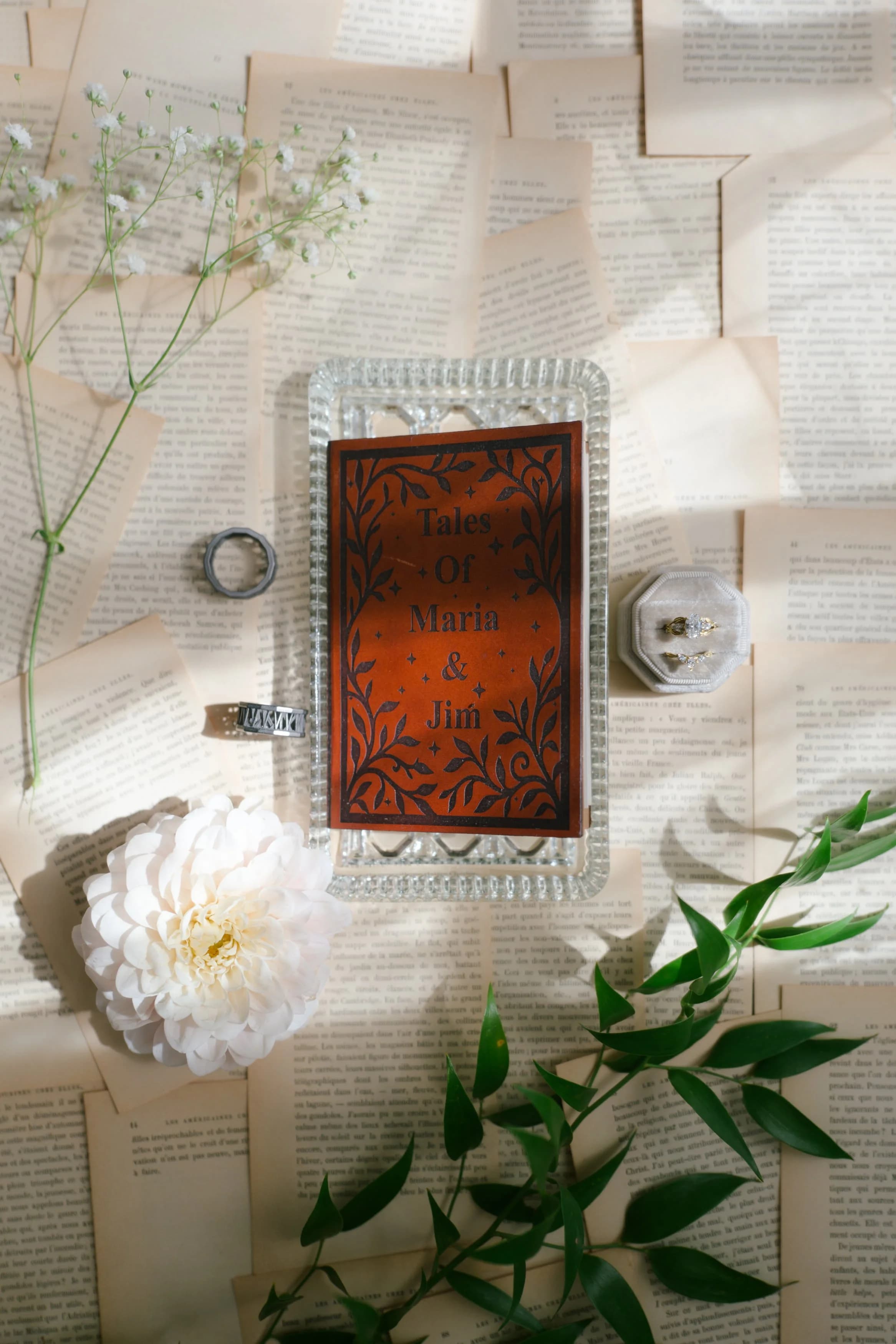 Laser-engraved leather book invitation on a vintage glass tray